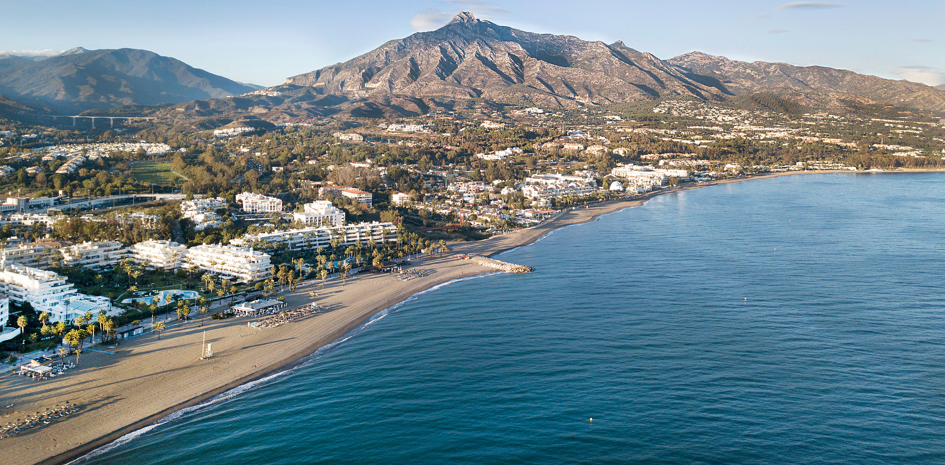Aerial view of Marbella coastline with mountains in the background, showcasing the Costa del Sol lifestyle.